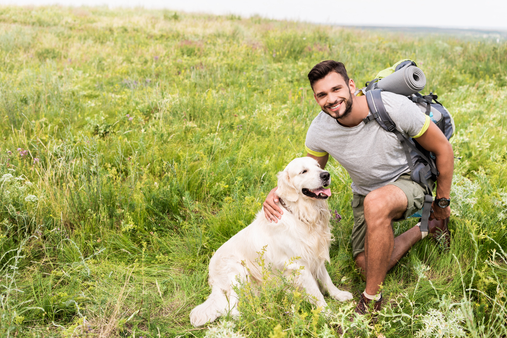 Smiling traveler with backpack and cute dog sitting
